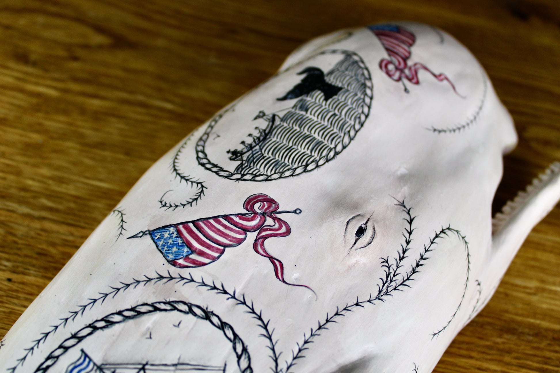 Hanging sperm whale sculpture by Laura Rotelli.  Sperm whale porcelain sculpture with scrimshaw designs of whaling scenes and ships painted on the surface.  Maritime art, marine art, folk art, Americana, patriotic art