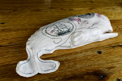 Hanging sperm whale sculpture by Laura Rotelli.  Sperm whale porcelain sculpture with scrimshaw designs of whaling scenes and ships painted on the surface.  Maritime art, marine art, folk art, Americana, patriotic art
