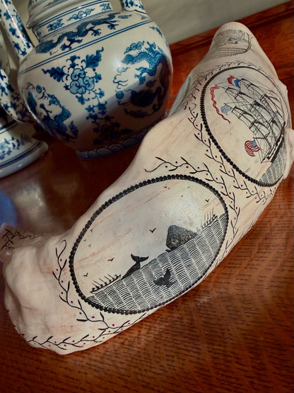 Angled view of Edward II on a cabinet beside blue and white ceramics, showing its decorated back.