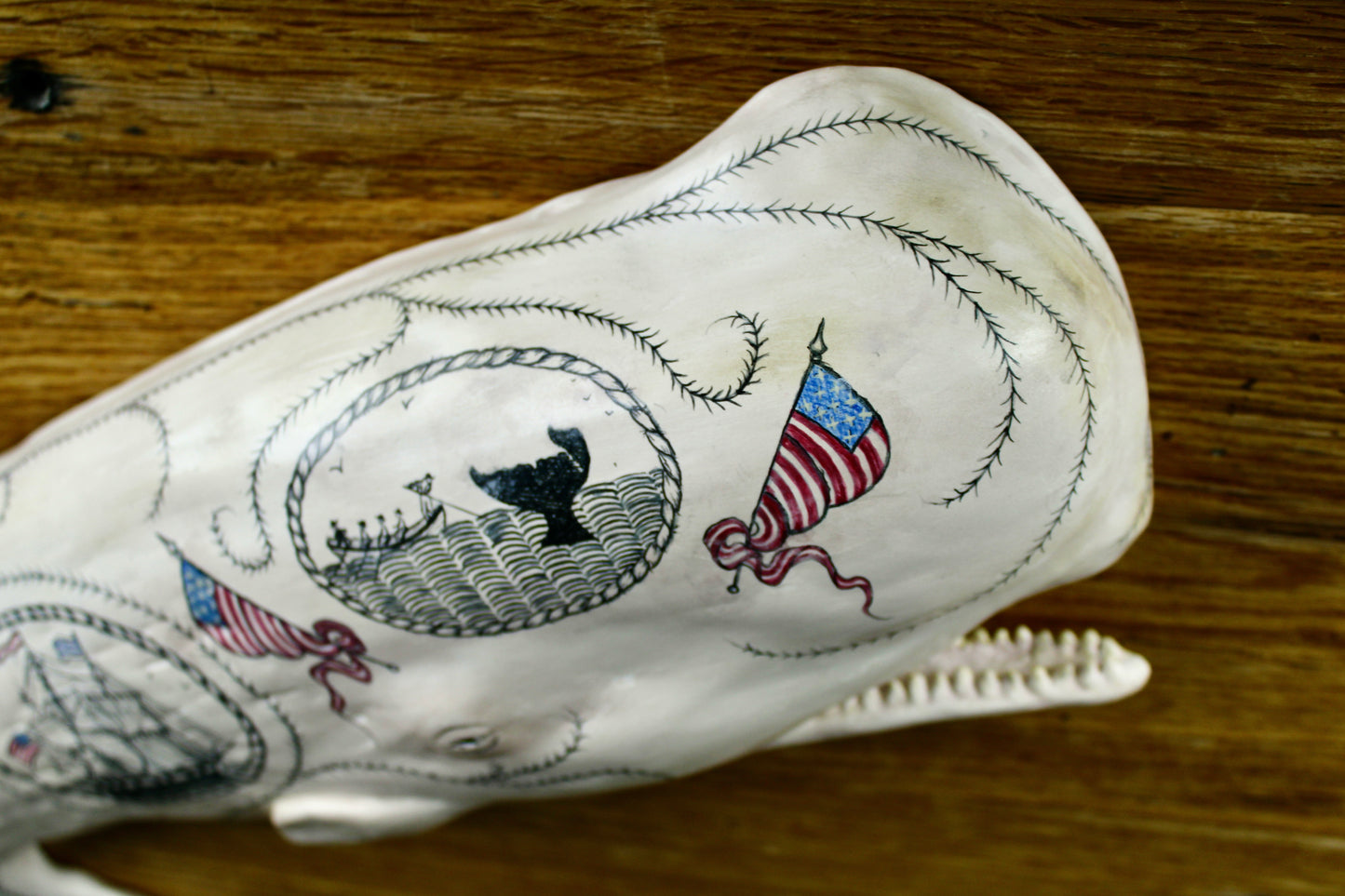 Hanging sperm whale sculpture by Laura Rotelli.  Sperm whale porcelain sculpture with scrimshaw designs of whaling scenes and ships painted on the surface.  Maritime art, marine art, folk art, Americana, patriotic art