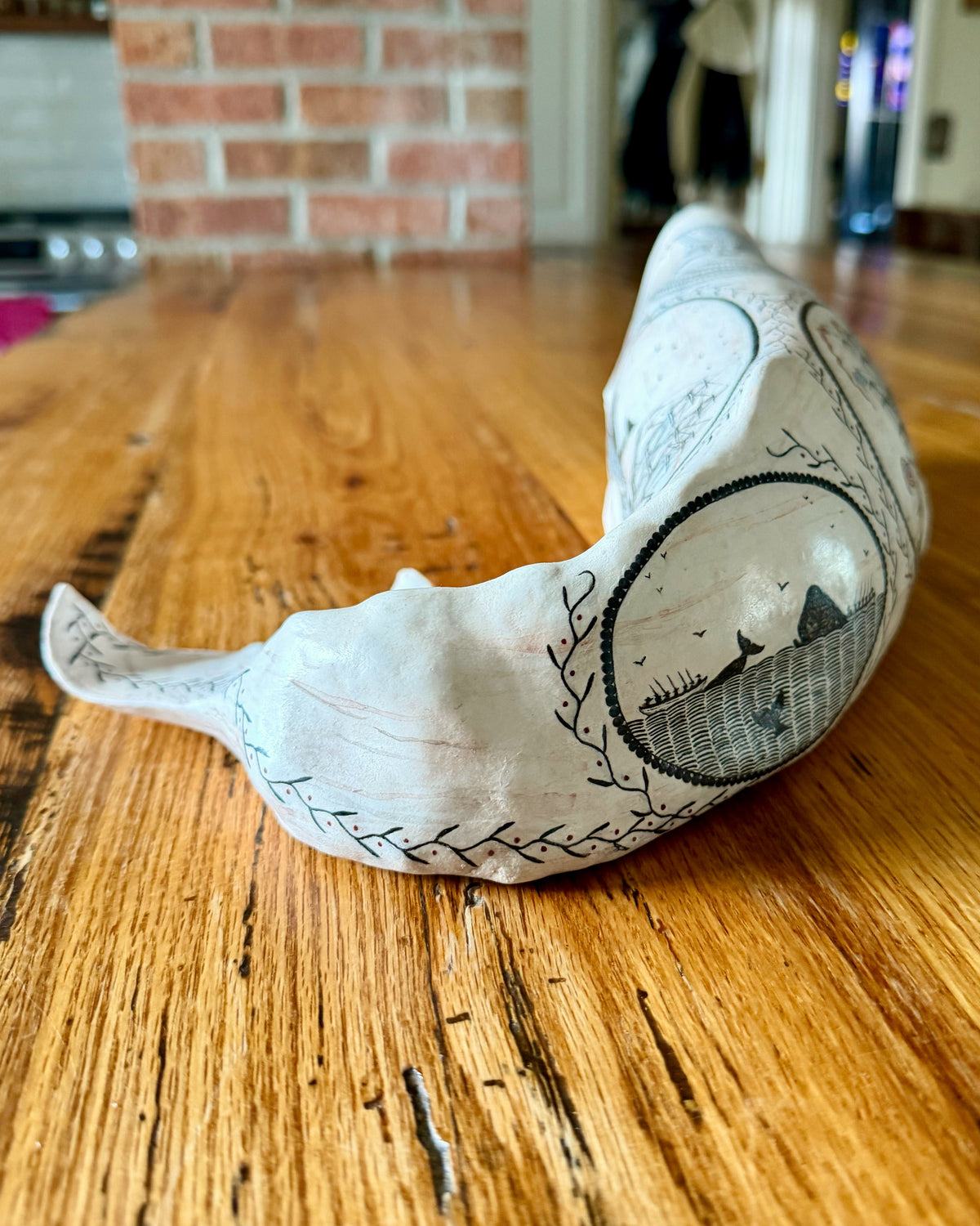 Tail-end view of Edward II showing the curved body, flukes, and oval whale scene.