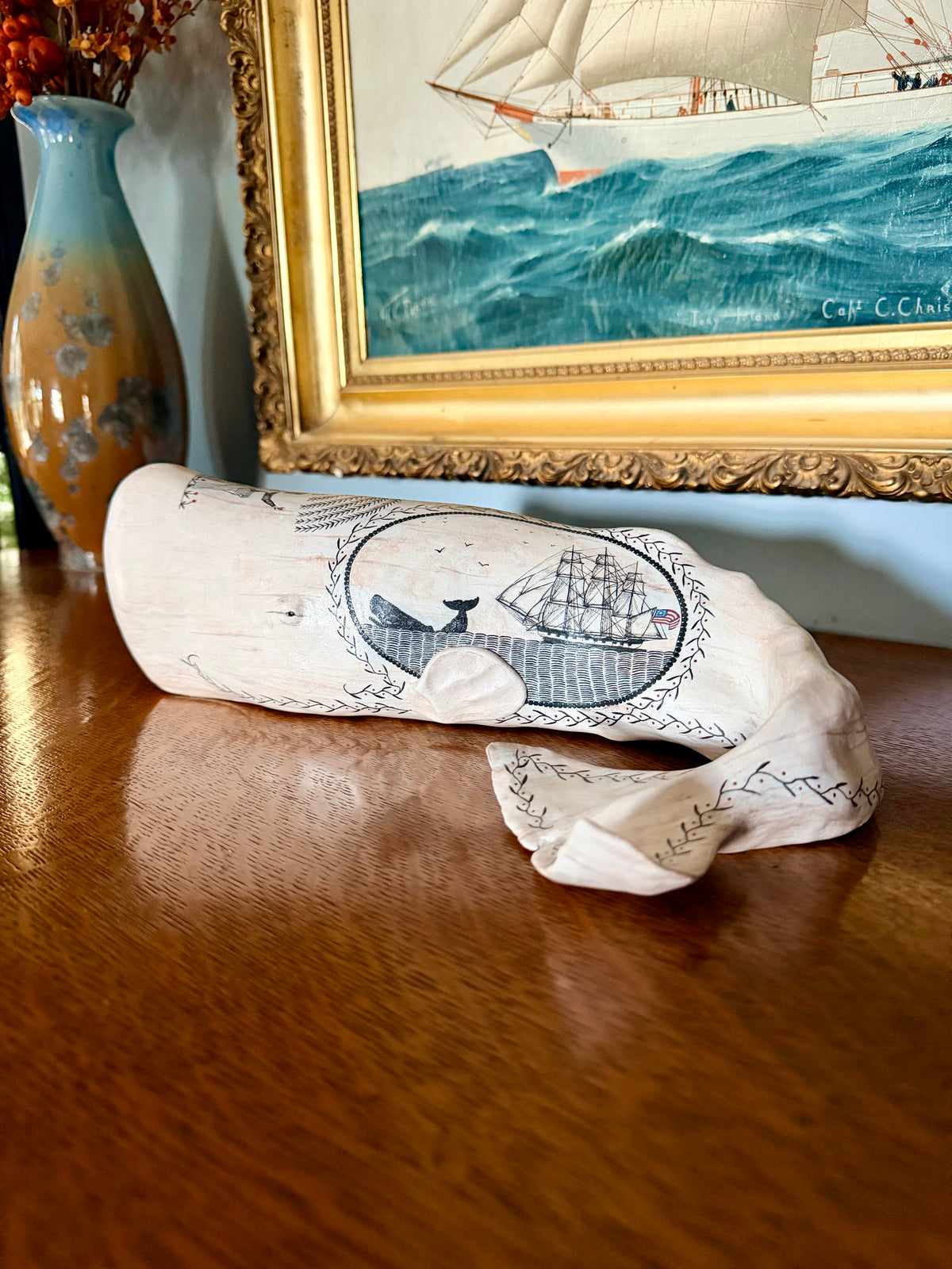 American contemporary folk art by Laura Rotelli.   Porcelain sperm whale sculpture with painted scrimshaw designs of sailing ships and whaling scenes, coastal maritime nautical artwork.