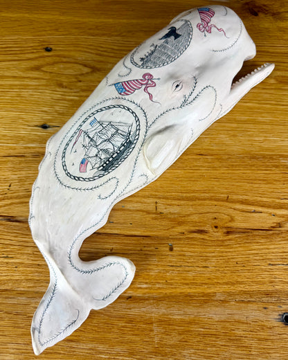 Hanging sperm whale sculpture by Laura Rotelli.  Sperm whale porcelain sculpture with scrimshaw designs of whaling scenes and ships painted on the surface.  Maritime art, marine art, folk art, Americana, patriotic art
