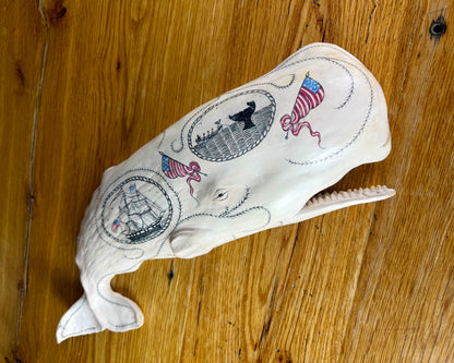 Hanging sperm whale sculpture by Laura Rotelli.  Sperm whale porcelain sculpture with scrimshaw designs of whaling scenes and ships painted on the surface.  Maritime art, marine art, folk art, Americana, patriotic art